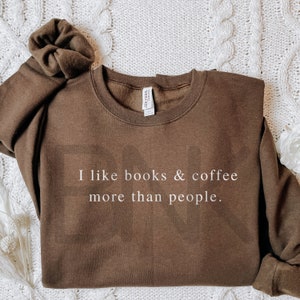 May include: A brown sweatshirt with the text "I like books & coffee more than people." printed in white.