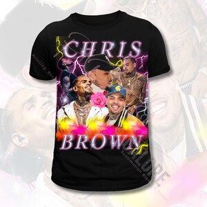 May include: Black t-shirt featuring a collage of images of Chris Brown. The images are surrounded by pink and yellow lightning bolts. The text "CHRIS BROWN" is in large pink letters.