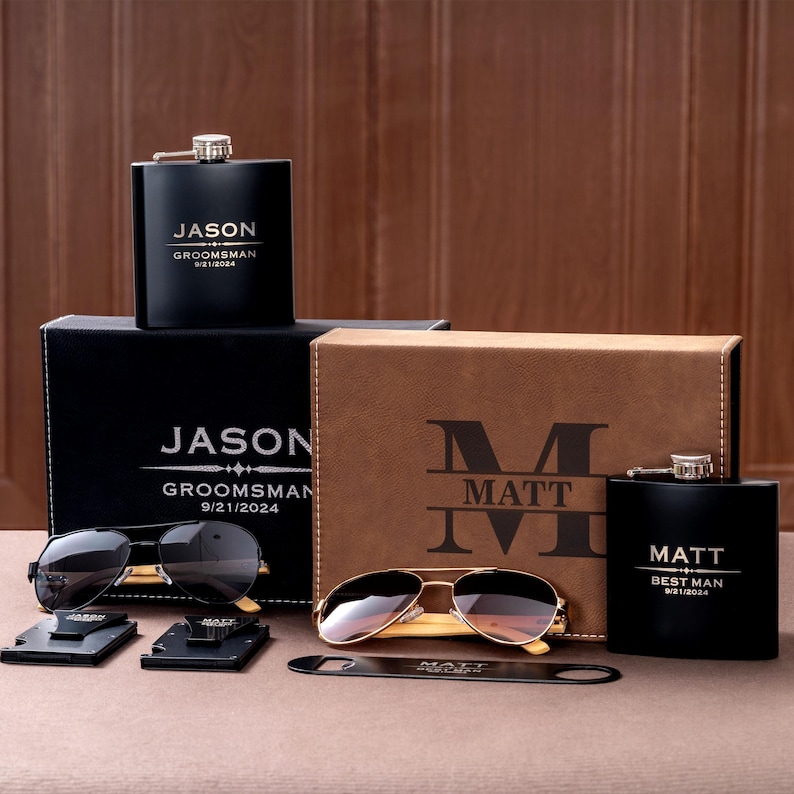 May include: A collection of personalized gifts, including black hip flasks, sunglasses, and a bottle opener. The flasks and boxes are engraved with names and dates. Sunglasses have black lenses and gold frames.