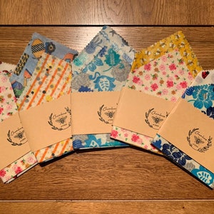 May include: A set of eight reusable food wraps with various colorful patterns. The wraps are made of beeswax, organic cotton, and tree resin. Each wrap is labeled with the brand name "Chambers & Co."