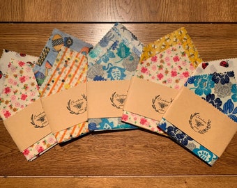 May include: A set of eight reusable food wraps with various colorful patterns. The wraps are made of beeswax, organic cotton, and tree resin. Each wrap is labeled with the brand name "Chambers & Co."