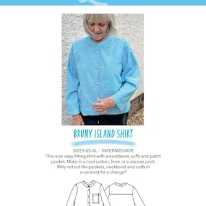 May include: A woman wearing a light blue long-sleeve shirt with a neckband and a patch pocket. The shirt is part of the "BRUNY ISLAND SHIRT" pattern from STUDIO 23 PATTERNS. The pattern includes sizes XS-XL.