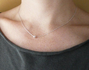 May include: A simple silver necklace with a small round pendant.