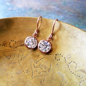 Tiny rose gold and cubic zirconia earrings. Sparkling stones are set in a thin rose gold filled bezel and suspended from comfortable 14K rose gold filled French ear wire.
