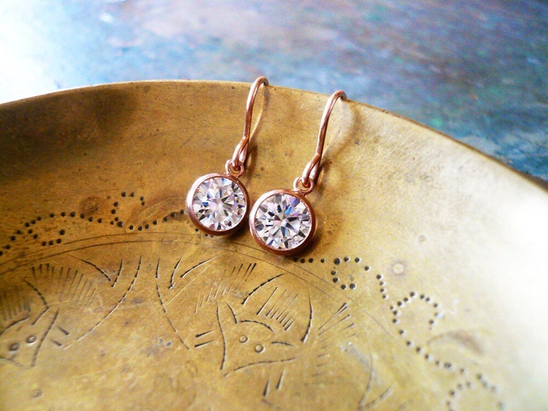 Tiny rose gold and cubic zirconia earrings. Sparkling stones are set in a thin rose gold filled bezel and suspended from comfortable 14K rose gold filled French ear wire.