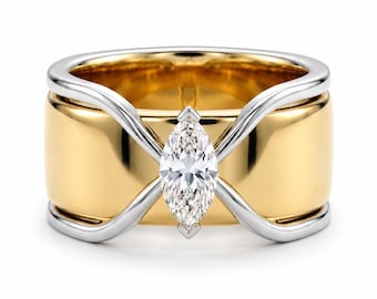 May include: A wide band ring featuring a polished yellow gold base and a contrasting silver-toned metal overlay that curves across the surface. A single marquise-cut clear gemstone is set vertically in the center of the overlapping metal design.