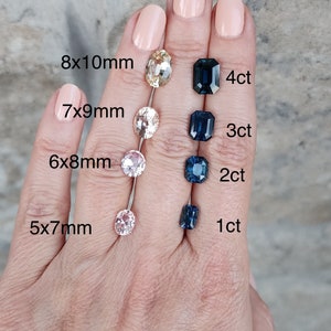 May include: A hand model wearing clear nail polish displays a size chart for sapphires. The chart shows the approximate measurements in millimetres and the corresponding carat weight for each sapphire. The sapphires are oval-shaped and range in size from 1 to 4 carats.