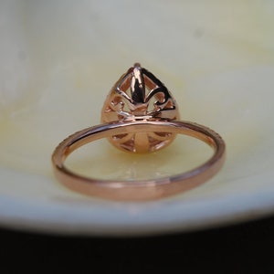 Puede incluir: Un anillo de compromiso de oro rosa con un engaste abierto en forma de pera. El anillo tiene un dise&ntilde;o delicado y filigrana.