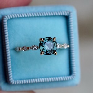 May include: A gold ring with a blue gemstone and a band of small diamonds.