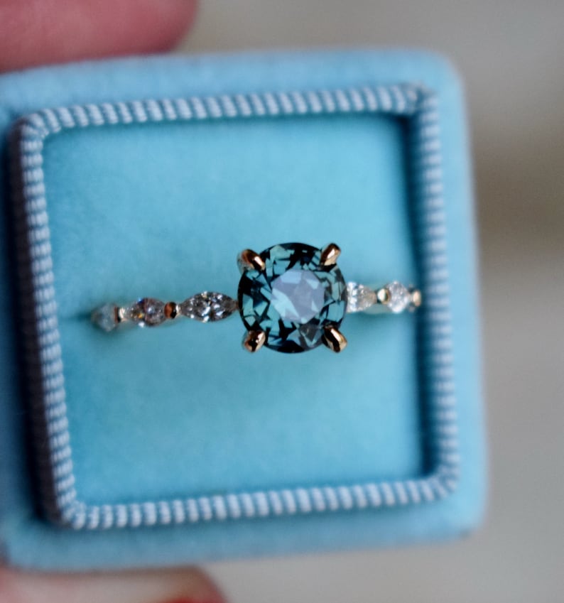 May include: A gold ring with a blue gemstone and a band of small diamonds.