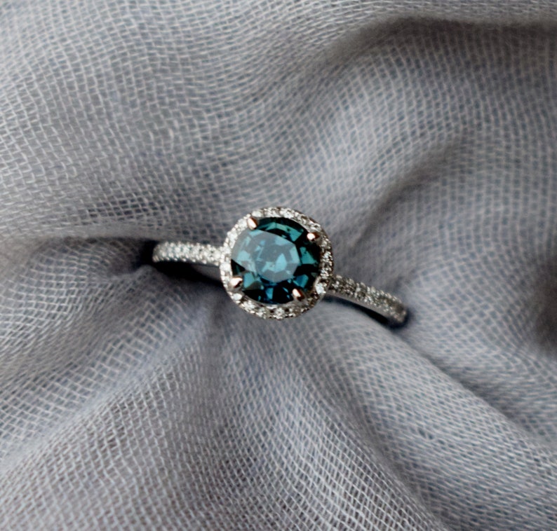 May include: A silver ring featuring a blue gemstone set in a halo of smaller diamonds.