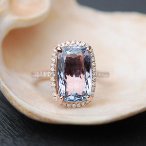 May include: A rose gold ring with a large, cushion-cut amethyst gemstone surrounded by a halo of smaller diamonds.