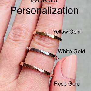 Puede incluir: Tres anillos de oro apilados en un dedo. El anillo superior es de oro amarillo, el anillo del medio es de oro blanco y el anillo inferior es de oro rosa. El texto "Select Personalization" est&aacute; en la parte superior de la imagen.