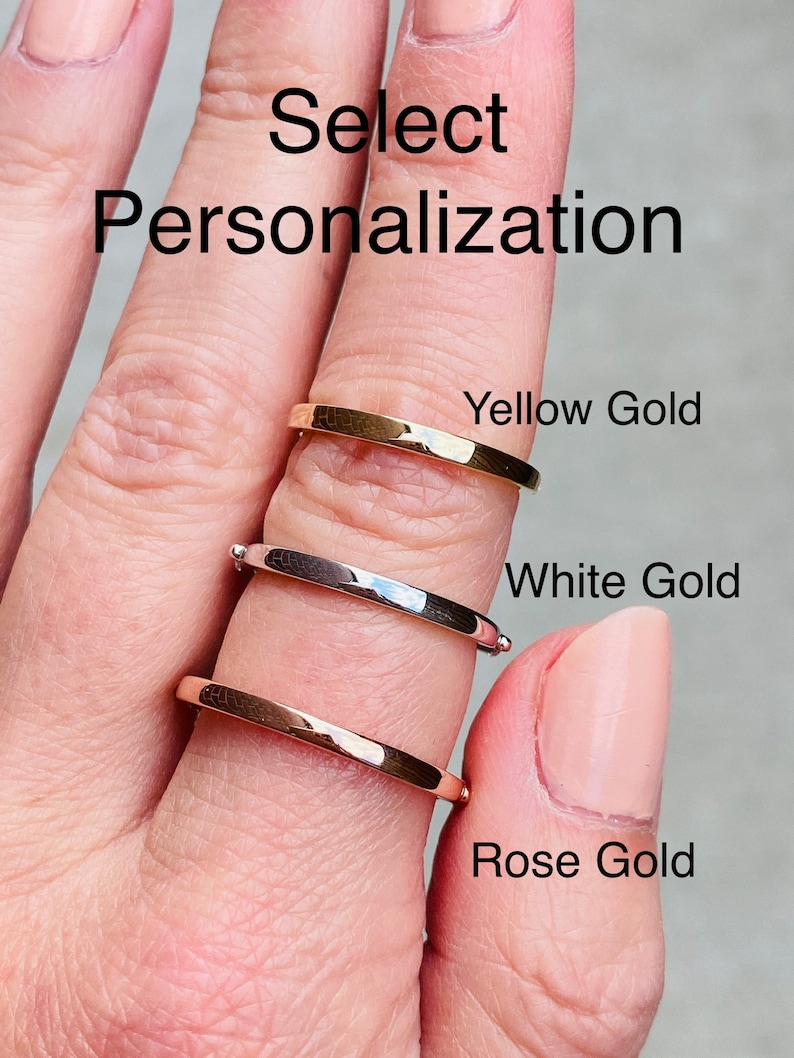 Puede incluir: Tres anillos de oro apilados en un dedo. El anillo superior es de oro amarillo, el anillo del medio es de oro blanco y el anillo inferior es de oro rosa. El texto "Select Personalization" est&aacute; en la parte superior de la imagen.