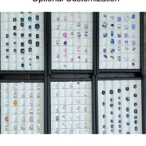 May include: A display of various gemstone options for a custom jewelry piece. The display shows a variety of colors and shapes, including blue, pink, and yellow gemstones. The text "Optional Customization" is at the top of the image. The text "If you prefer this setting with a different center stone" is at the bottom of the image.