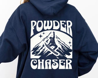 Puede incluir: Sudadera con capucha azul marino con un gráfico blanco que presenta una montaña, un snowboarder y las palabras "POWDER CHASER". La sudadera tiene una capucha con cordón y un bolsillo de canguro. También es visible el texto "MADE WITH LOVE BY ANIMAL PARC APPAREL".