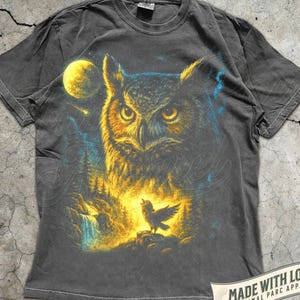 May include: Pepper-coloured t-shirt with an owl illustration, full moon, and forest scene. A singing bird is also featured. The text reads "MADE WITH LOVE BY ANIMAL PARC APPAREL".
