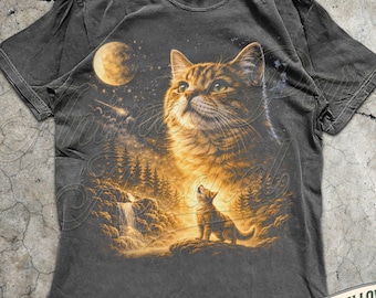 May include: Dark gray t-shirt featuring a large cat illustration with a moon, waterfall, and forest scene. A smaller cat is also depicted. The shirt includes the text "MADE WITH LOVE BY ANIMAL PARC APPAREL" and the color is "PEPPER".