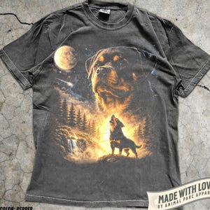 Könnte beinhalten: Pfefferfarbenes T-Shirt mit einem Rottweiler-Hundedesign und einem Wolf, der den Mond anheult. Die Grafik zeigt einen Wald, einen Wasserfall und den Text "MADE WITH LOVE BY ANIMAL PARC APPAREL".