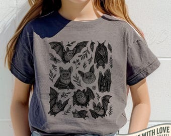 May include: A gray t-shirt with a black bat graphic. The design features various bat illustrations, leaves, and a butterfly. The shirt has short sleeves and the text "MADE WITH LOVE BY ANIMAL PARC APPAREL". The color is pepper.