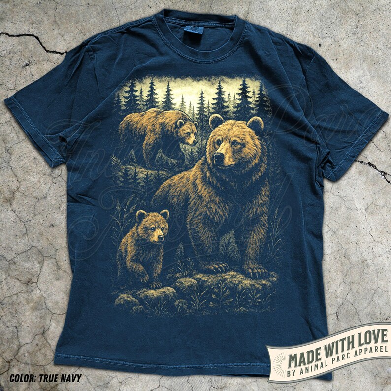 May include: True navy blue t-shirt featuring a detailed illustration of three brown bears in a forest setting. The design includes a mother bear and two cubs, with a backdrop of pine trees. The text "MADE WITH LOVE BY ANIMAL PARC APPAREL" is visible.