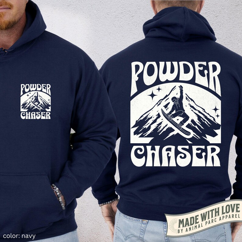 May include: Navy blue hoodie featuring a white mountain and snowboarder graphic, with the words "POWDER CHASER". The hoodie has a front pocket and a drawstring hood. The colour is navy.