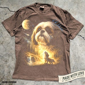 May include: Espresso-colored t-shirt featuring a detailed illustration of a Shih Tzu dog with a celestial background. The design includes a moon, stars, and a forest scene with a waterfall. The text "MADE WITH LOVE" is visible.