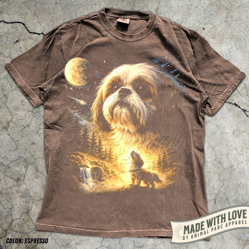 May include: Espresso-colored t-shirt featuring a detailed illustration of a Shih Tzu dog with a celestial background. The design includes a moon, stars, and a forest scene with a waterfall. The text "MADE WITH LOVE" is visible.
