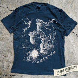Pode incluir: T-shirt azul marinho com uma ilustra&ccedil;&atilde;o branca de coelhos, raios e uma lua cheia. O design inclui o texto "MADE WITH LOVE BY ANIMAL PARC APPAREL". A t-shirt tem mangas curtas e gola redonda. A cor &eacute; 'True Navy'.