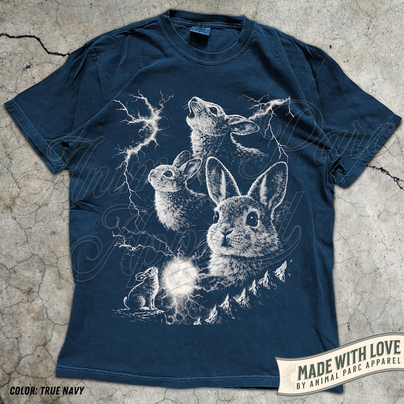 Pode incluir: T-shirt azul marinho com uma ilustra&ccedil;&atilde;o branca de coelhos, raios e uma lua cheia. O design inclui o texto "MADE WITH LOVE BY ANIMAL PARC APPAREL". A t-shirt tem mangas curtas e gola redonda. A cor &eacute; 'True Navy'.
