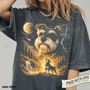 May include: Pepper-coloured t-shirt with a detailed illustration of a Schnauzer dog under a full moon, with a smaller dog howling in a forest scene. The text "MADE WITH LOVE" and "COLOR: PEPPER" are also visible.