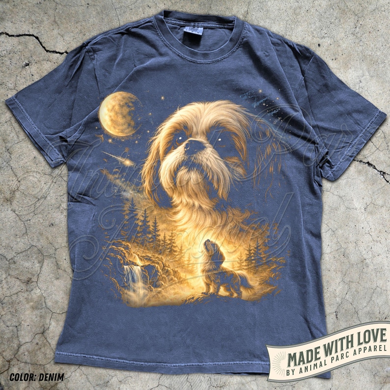 May include: Denim blue t-shirt featuring a detailed illustration of a Shih Tzu dog under a full moon and starry night sky. The design includes a waterfall and forest scene. The text "MADE WITH LOVE BY ANIMAL PARC APPAREL" is printed on the bottom right.