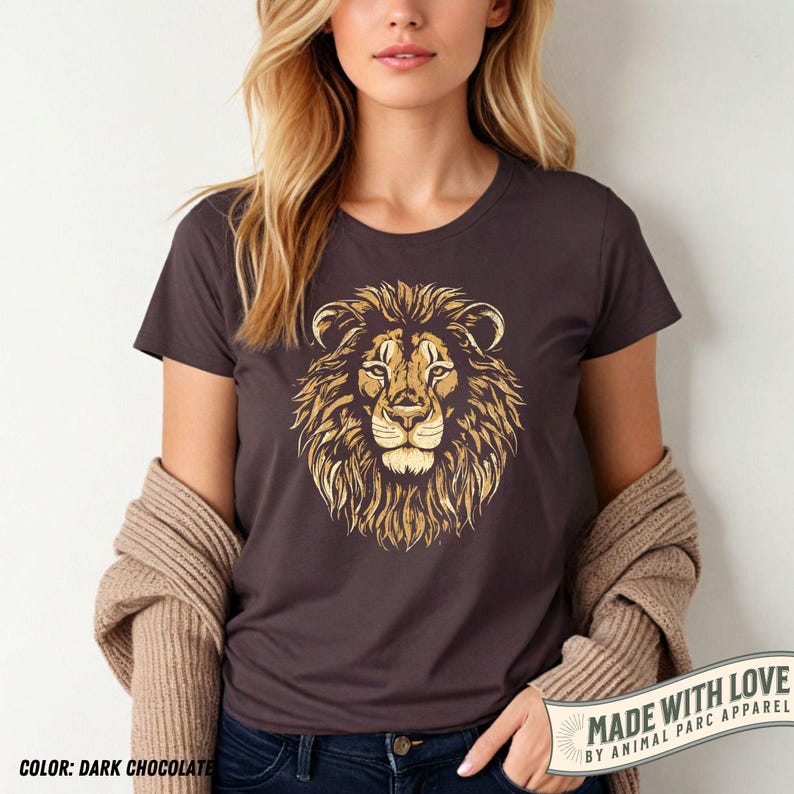 May include: Dark chocolate-colored t-shirt featuring a detailed golden lion's head graphic. The shirt has a crew neck and short sleeves. The text "MADE WITH LOVE" and "COLOR: DARK CHOCOLATE" are visible.