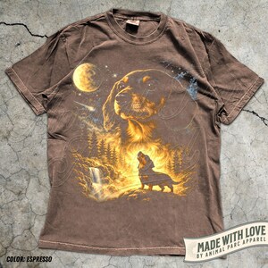 May include: Espresso-colored t-shirt featuring a detailed graphic of a dog with a forest and waterfall scene under a starry sky and moon. The shirt includes the text "MADE WITH LOVE BY ANIMAL PARC APPAREL".