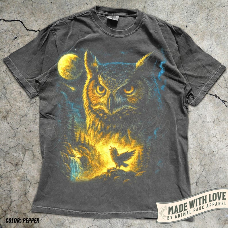 May include: Pepper-coloured t-shirt with an owl illustration, full moon, and forest scene. A singing bird is also featured. The text reads "MADE WITH LOVE BY ANIMAL PARC APPAREL".