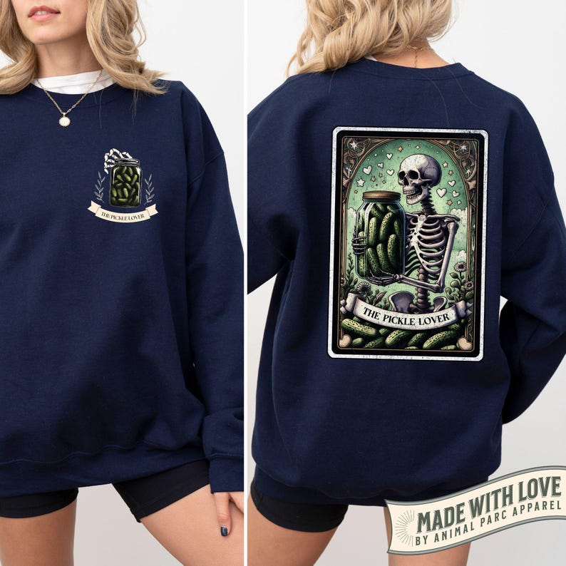 Pu&ograve; includere: Felpa blu navy con grafica frontale di un barattolo di sottaceti e la scritta "THE PICKLE LOVER". Il retro presenta uno scheletro che tiene un barattolo di sottaceti con lo stesso testo. Girocollo.