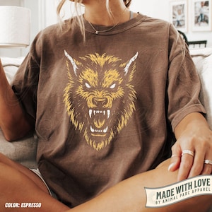 May include: Espresso-coloured t-shirt with a yellow and white snarling wolf head illustration. The graphic is on the front of the shirt. The shirt is part of the Animal Parc Apparel collection.