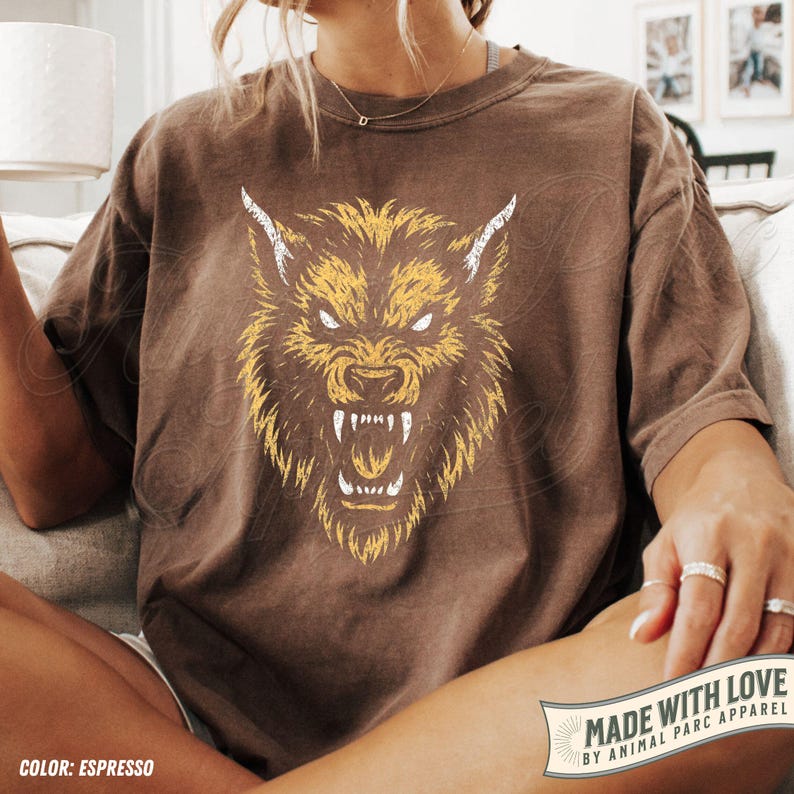 May include: Espresso-coloured t-shirt with a yellow and white snarling wolf head illustration. The graphic is on the front of the shirt. The shirt is part of the Animal Parc Apparel collection.