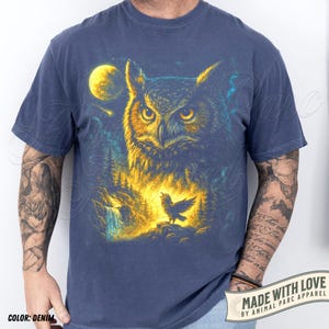 May include: Denim blue t-shirt with a detailed illustration of an owl in yellow and blue, a full moon, and a singing bird in a forest. The text "MADE WITH LOVE BY ANIMAL PARC APPAREL" is printed on the bottom right.