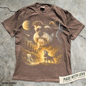 May include: Espresso-coloured t-shirt with a detailed graphic of a Schnauzer dog howling at the moon, set against a waterfall and forest backdrop. The shirt includes the text "MADE WITH LOVE BY ANIMAL PARC APPAREL" and "COLOR: ESPRESSO".