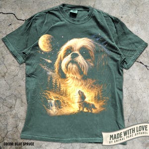 May include: Blue spruce-colored t-shirt featuring a detailed illustration of a dog with a celestial background. The design includes a moon, stars, and a smaller dog in a forest scene. The text "MADE WITH LOVE BY ANIMAL PARC APPAREL" is visible.