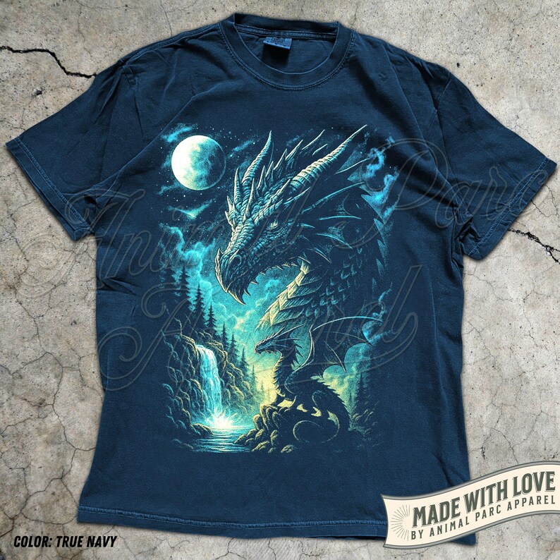 May include: True navy blue t-shirt featuring a detailed dragon illustration with a waterfall, moon, and forest scene. The dragon is depicted in shades of blue and teal. The text "MADE WITH LOVE BY ANIMAL PARC APPAREL" is visible.