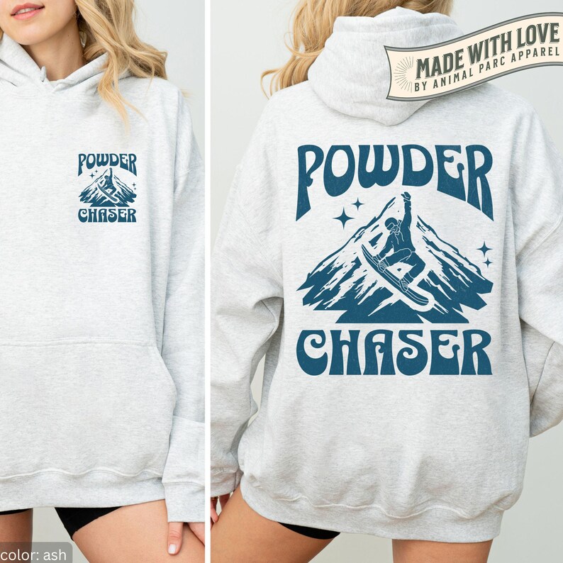 May include: Light grey hoodie with a front pocket and hood. The front has a small graphic with the words "POWDER CHASER" and a mountain design. The back shows a larger version of the same design, including a snowboarder.