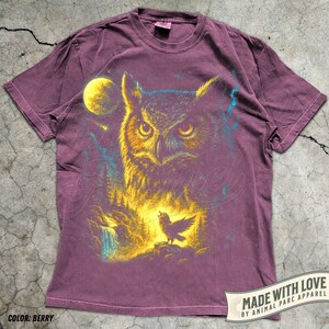 May include: Berry-coloured t-shirt with a detailed illustration of an owl, full moon, forest, and a singing bird. The design uses yellow, blue, and purple. The text "MADE WITH LOVE BY ANIMAL PARC APPAREL" is printed on the bottom right.