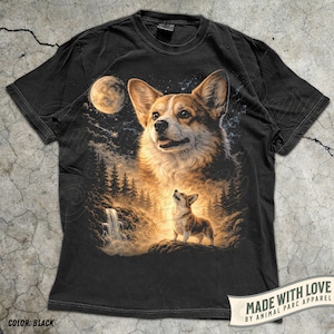 May include: Black t-shirt featuring a detailed illustration of a Corgi dog with a forest and waterfall scene under a moonlit sky. The design includes a large Corgi and a smaller one looking up. The text "MADE WITH LOVE" is visible.