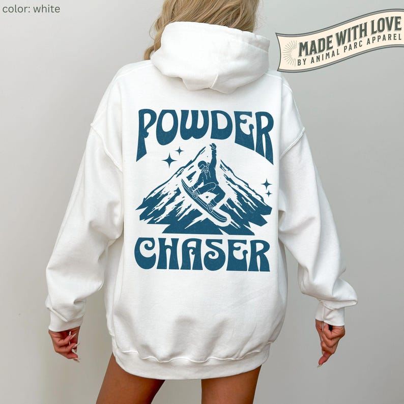 May include: White hoodie with a blue graphic on the back. The graphic features a mountain scene with a snowboarder and the words "POWDER CHASER". The hoodie also has the text "MADE WITH LOVE BY ANIMAL PARC APPAREL".