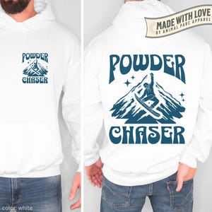 May include: White hoodie with a blue graphic on the front and back. The front graphic says "POWDER CHASER" with a mountain illustration. The back graphic features a snowboarder on a mountain with the words "POWDER CHASER".