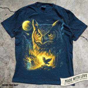 May include: True navy blue t-shirt with a detailed illustration of an owl, a full moon, and a small bird. The design includes a forest scene with a waterfall. The text "MADE WITH LOVE" is visible.