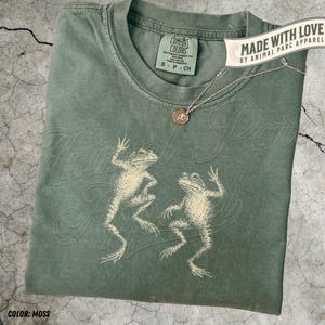 May include: A white ceramic mug with a black handle and the text "But first, coffee" in a black, handwritten-style font. The mug is on a white surface.