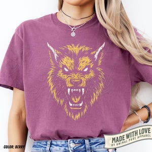 May include: Berry-coloured t-shirt with a yellow and white snarling wolf head illustration. The shirt includes the text "MADE WITH LOVE BY ANIMAL PARC APPAREL". It is a short-sleeved crew neck.